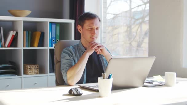 Jeune entrepreneur masculin travaille au bureau à domicile à l'ordinateur. Lieu de travail de pigiste ou d'étudiant. Concept de télétravail et d'éducation. — Video