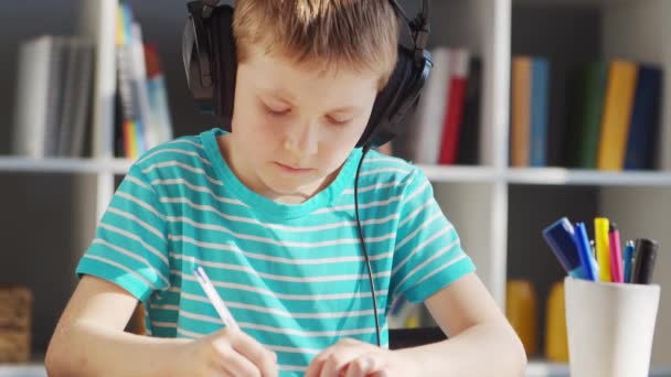 Boy está haciendo su tarea en la mesa. Lindo niño está aprendiendo en casa con la ayuda de libros de texto y materiales escolares. Concepto de estudio y educación. — Vídeos de Stock