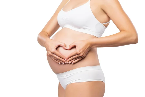 Ung gravid kvinna i baddräkt. Flicka som väntar barn och vidrör magen isolerad på vit bakgrund. Närbild. — Stockfoto