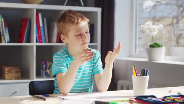 Junge erledigt seine Hausaufgaben am Tisch. Nettes Kind lernt zu Hause mit Hilfe von Lehrbüchern und Schulmaterialien. Studien- und Ausbildungskonzept. — Stockvideo