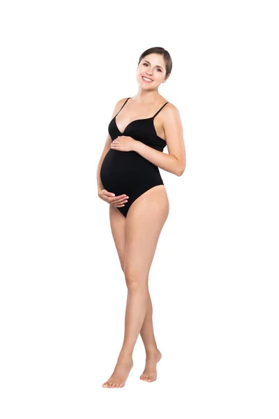 Young pregnant woman in black swimsuit. Girl expecting a baby and touching her belly isolated on white background. — Stock Photo, Image