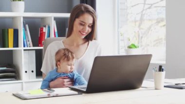 Genç Kadın yeni doğmuş bebeğiyle evde otururken çalışıyor. Kadın Girişimci, Freelancer ya da Öğrenci 'nin işyeri. Uzaktan Çalışma ve Eğitim Konsepti.