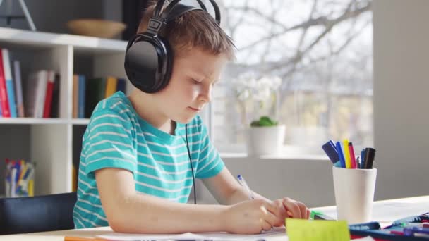 Il ragazzo sta facendo i compiti a tavola. Cute Child sta imparando a casa con l'aiuto di libri di testo e materiali scolastici. Concetto di studio e istruzione. — Video Stock