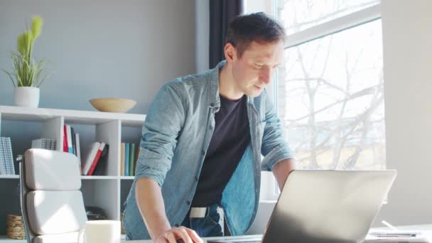 Joven empresario masculino trabaja en la oficina en casa en la computadora. Lugar de trabajo del freelancer o estudiante. Trabajo remoto y concepto de educación. — Vídeos de Stock