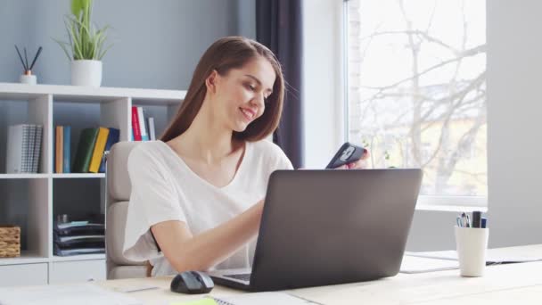 Mujer joven trabaja en el Ministerio del Interior usando computadora y Smertphone. Lugar de trabajo de Emprendedora, Freelancer o Estudiante. Trabajo remoto y concepto de educación. — Vídeos de Stock