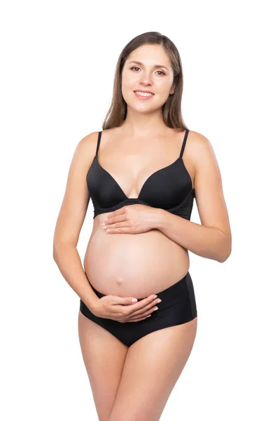 黒い水着を着た若い妊婦さん 赤ん坊を期待し 白い背景に隔離された彼女の腹に触れる女の子 スタジオイメージ — ストック写真