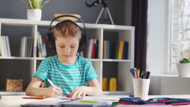 Pojken gör sina läxor vid bordet. Söta barn är att lära sig hemma med hjälp av läroböcker och skolmaterial. Studie- och utbildningsidé. — Stockvideo