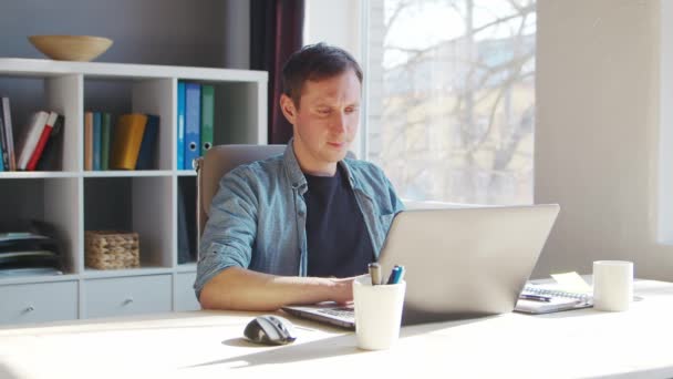 Joven empresario masculino trabaja en la oficina en casa en la computadora. Lugar de trabajo del freelancer o estudiante. Trabajo remoto y concepto de educación. — Vídeos de Stock