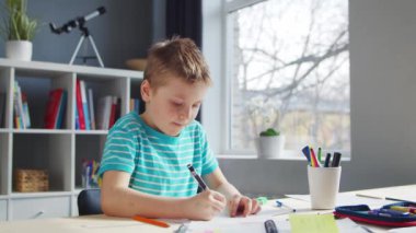 Çocuk Masa 'da ödevini yapıyor. Şirin Çocuk, Ders kitapları ve okul malzemelerinin yardımıyla evde öğreniyor. Eğitim ve Öğrenim Konsepti.