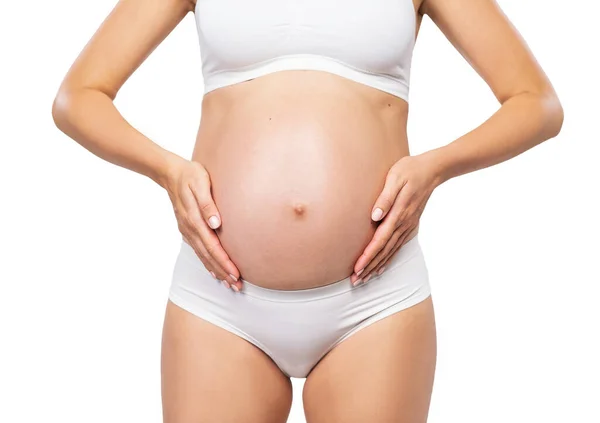 Ung gravid kvinna i baddräkt. Flicka som väntar barn och vidrör magen isolerad på vit bakgrund. Närbild. — Stockfoto