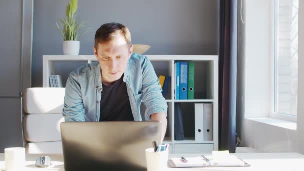 Joven empresario masculino trabaja en la oficina en casa en la computadora. Lugar de trabajo del freelancer o estudiante. Trabajo remoto y concepto de educación. — Vídeos de Stock