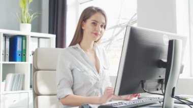 Ofiste bilgisayar kullanan genç bir kadın. Girişimci, Yönetici ya da İş Kadını 'nın işyeri. Uzaktan Çalışma ve Eğitim Konsepti.