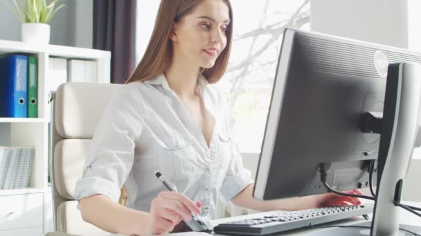 La joven trabaja en la oficina usando la computadora. Lugar de trabajo de Empresario, Gerente o Empresaria. Trabajo remoto y concepto de educación. — Vídeos de Stock