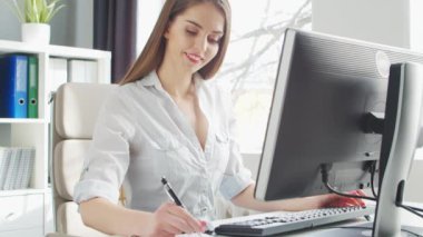Ofiste bilgisayar kullanan genç bir kadın. Girişimci, Yönetici ya da İş Kadını 'nın işyeri. Uzaktan Çalışma ve Eğitim Konsepti.