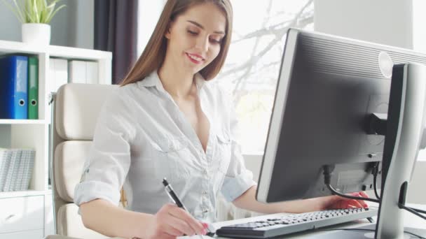 Młoda kobieta pracuje w biurze za pomocą komputera. Miejsce pracy przedsiębiorcy, menedżera lub bizneswoman. Koncepcja pracy zdalnej i edukacji. — Wideo stockowe