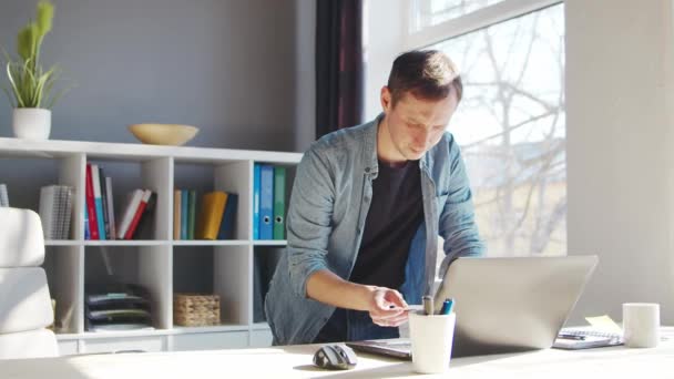 Joven hace compras en Internet usando una tarjeta de crédito bancaria. La persona trabaja en casa en la computadora. Concepto de compras en línea y sistemas de pago. — Vídeos de Stock