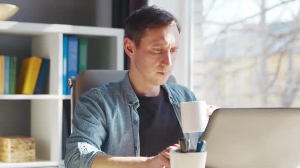 Jeune entrepreneur masculin travaille au bureau à domicile à l'ordinateur. Lieu de travail de pigiste ou d'étudiant. Concept de télétravail et d'éducation. — Video