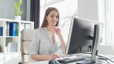 Ofiste bilgisayar kullanan genç bir kadın. Girişimci, Yönetici ya da İş Kadını 'nın işyeri. Uzaktan Çalışma ve Eğitim Konsepti.