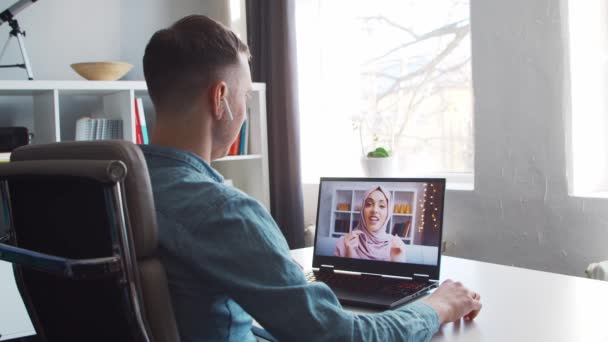 Pojkvännen och hans muslimska flickvän har ett samtal online via internet. Ungdomar sitter hemma och har telefonkonferens. Pratar man och kvinna. Fjärrdatum och kommunikationskoncept. — Stockvideo