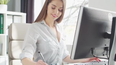 Ofiste bilgisayar kullanan genç bir kadın. Girişimci, Yönetici ya da İş Kadını 'nın işyeri. Uzaktan Çalışma ve Eğitim Konsepti.