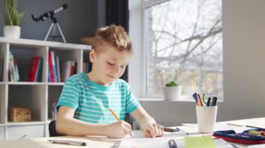 Çocuk Masa 'da ödevini yapıyor. Şirin Çocuk, Ders kitapları ve okul malzemelerinin yardımıyla evde öğreniyor. Öğrenim ve Eğitim Konsepti.