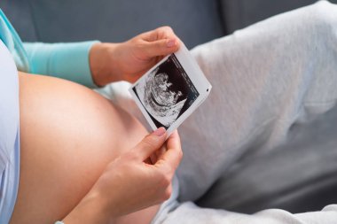 Genç hamile kadın evde dinleniyor ve bebek bekliyor. Hamilelik, annelik, sağlık ve yaşam tarzı kavramı.