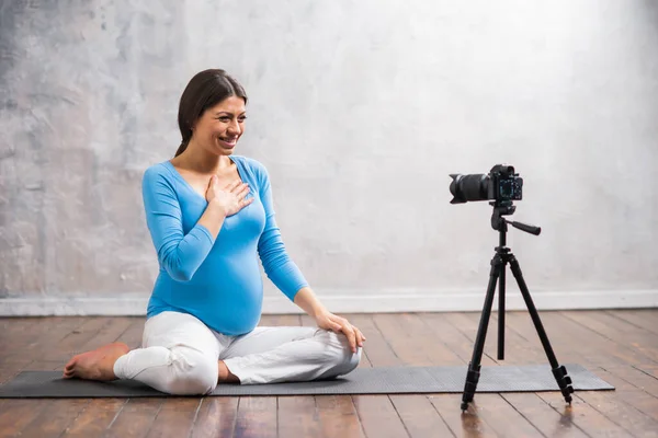 A young pregnant woman makes a vlog about pregnancy. The influencer records videos or streams on a camera at home. — Stock Photo, Image