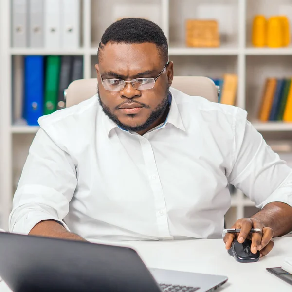 Werkplaats op kantoor. Jonge Afro-Amerikaanse man werkt met behulp van een computer en andere apparaten. Afstandswerkconcept. — Stockfoto