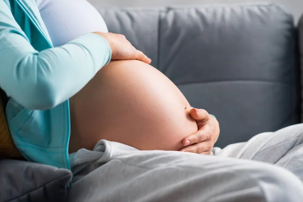 Ung gravid kvinna vilar hemma och väntar barn. Graviditet, moderskap, hälsovård och livsstil. — Stockfoto