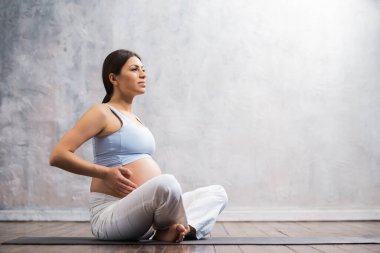 Genç hamile kadın yoga yapıyor ve evde meditasyon yapıyor. Sağlık, farkındalık, rahatlama ve sağIık kavramı.