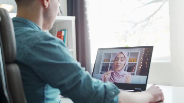 Хлопець і його мусульманська дівчина мають онлайн розмову по телефону через Інтернет. Молоді люди сидять вдома і мають конференц-дзвінок. Говорить чоловік і жінка. Віддалена дата і концепція зв'язку . — стокове відео