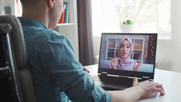 Boyfriend and his muslim girlfriend have online call conversation via internet. Young people are sitting at home and have conference call. Talking man and woman. Remote date and communication concept. — ストック動画