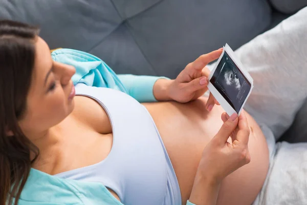 Genç hamile kadın evde dinleniyor ve bebek bekliyor. Hamilelik, annelik, sağlık ve yaşam tarzı kavramı. — Stok fotoğraf