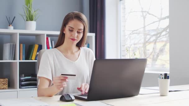 Молода жінка здійснює онлайн-покупки в Інтернеті за допомогою банківської кредитної картки. Робоче місце жінки-підприємця, фрілансера або студента. Концепція платіжних систем . — стокове відео