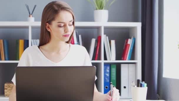 Jonge vrouw werkt bij Binnenlandse Zaken met behulp van de computer. Werkplaats van vrouwelijke ondernemer, freelancer of student. Concept telewerken en onderwijs. — Stockvideo