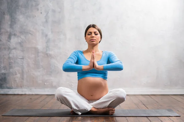 Young pregnant woman doing yoga exercises and meditating at home. Health care, mindfulness, relaxation and wellness concept. — Stock Photo, Image