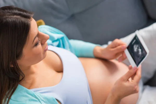 Genç hamile kadın evde dinleniyor ve bebek bekliyor. Hamilelik, annelik, sağlık ve yaşam tarzı kavramı. — Stok fotoğraf