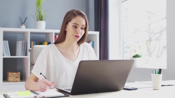 Jovem trabalha no Home Office usando o computador. Ela tem uma chamada de conferência. Local de trabalho de Empresário Feminino, Freelancer ou Estudante. Conceito de Trabalho Remoto e Educação. — Vídeo de Stock