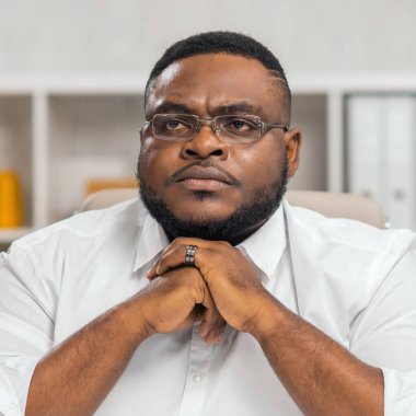 Ofisteki işyerinde. Genç Afro-Amerikalı bir adam bilgisayar ve diğer cihazları kullanarak çalışıyor. Uzak görev konsepti.