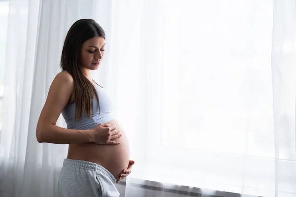 Junge schwangere Frau ruht sich zu Hause aus und erwartet ein Baby. Schwangerschaft, Mutterschaft, Gesundheitsfürsorge und Lebensstil-Konzept. — Stockfoto