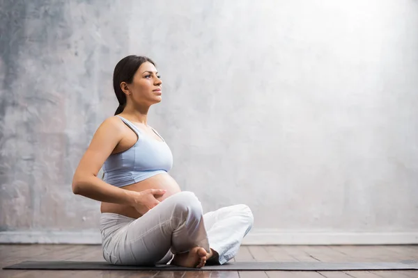 Jovem grávida fazendo exercícios de ioga e meditando em casa. Cuidados de saúde, atenção plena, relaxamento e conceito de bem-estar. — Fotografia de Stock