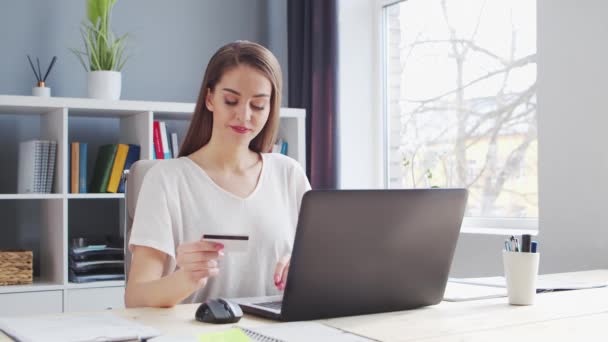 Молодая женщина делает онлайн покупки в Интернете с помощью банковской кредитной карты. Рабочее место предпринимательницы, фрилансера или студентки. Концепция платежных систем. — стоковое видео