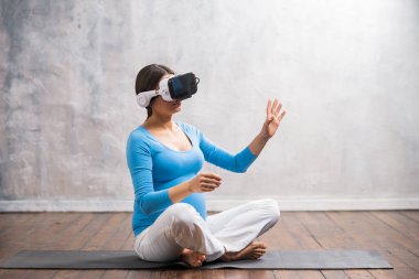 Video kasklı hamile bir kadın. Evde sanal bir simülatörde bir çocuğun doğumuna hazırlanıyor. Gelişmiş gerçeklik teknolojisi.