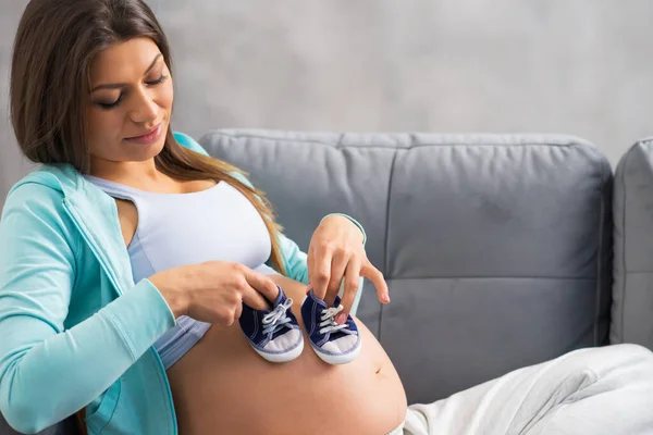 Junge schwangere Frau ruht sich zu Hause aus und erwartet ein Baby. Schwangerschaft, Mutterschaft, Gesundheitsfürsorge und Lebensstil-Konzept. Stockfoto