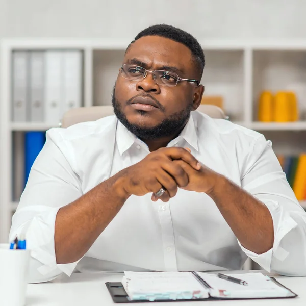 Ofisteki işyerinde. Genç Afro-Amerikalı bir adam bilgisayar ve diğer cihazları kullanarak çalışıyor. Uzak görev konsepti.