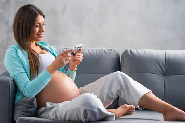 Jovem grávida está descansando em casa e esperando um bebê. Gravidez, maternidade, cuidados de saúde e estilo de vida conceito. — Fotografia de Stock