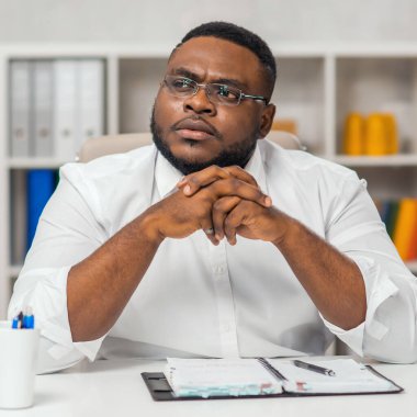 Ofisteki işyerinde. Genç Afro-Amerikalı bir adam bilgisayar ve diğer cihazları kullanarak çalışıyor. Uzak görev konsepti.