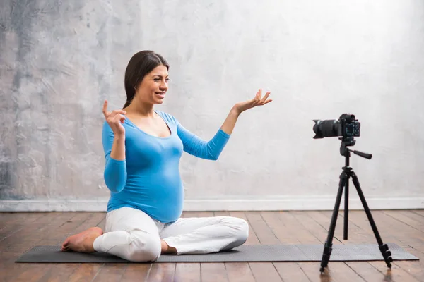 A young pregnant woman makes a vlog about pregnancy. The influencer records videos or streams on a camera at home. — Stock Photo, Image
