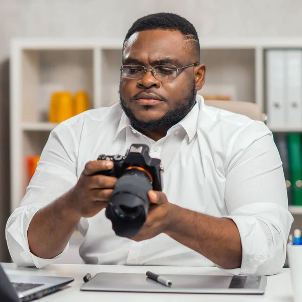 Молодий афро-американський фотограф працює в домашньому офісі. Дистанційна концепція роботи. Стокове Фото