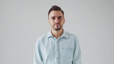 Young Caucasian Brunet Man is Looking at the Camera on a Light Gray Background. Studio Male Face Portrait. Natural Day Light.